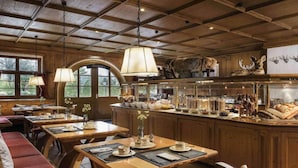 A rustic dining area with wooden tables, benches, and a central island with kitchenware. - Sunday Hotel Garmisch Partenkirchen Standard Twin Room (Garmisch-Partenkirchen)