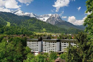 Ein Hotel mit modernem Design, umgeben von üppiger Vegetation und Bergen.