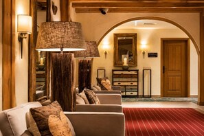 Eine Lobby mit rotem Teppich, einem hölzernen Empfangstresen, einem wandmontierten Spiegel und einem Schild mit der Aufschrift 'Willkommen im Haus'.