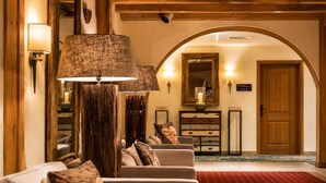A lobby with a red carpet, a wooden reception desk, a wall-mounted mirror, and a sign that reads 'Willkommen im Haus'. - Sunday Hotel Garmisch Partenkirchen Junior Suite (Garmisch-Partenkirchen)