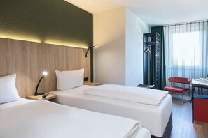 Habitación de hotel con dos camas, un escritorio, una silla y un armario.