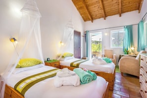 Una habitación con dos camas, cada una con dosel, mesitas de noche y vistas al exterior.