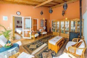 A cozy living room with a wooden ceiling, a large bookshelf, and a dining area with a table and chairs. - Moinhos Velhos Juice Detox & Yoga (Lagos)