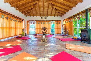 A yoga studio with wooden beams, orange curtains, and mats. - Moinhos Velhos Juice Detox & Yoga (Lagos)