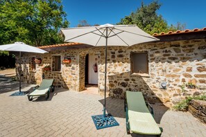 A stone building with two outdoor lounge chairs and umbrellas, a fire extinguisher, and a small window. - Moinhos Velhos Juice Detox & Yoga (Lagos)