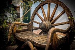 A rustic wooden bench with a large wheel, surrounded by greenery. - Moinhos Velhos Juice Detox & Yoga (Lagos)