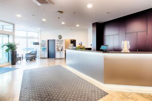 Ein moderner Empfangsbereich mit einer Rezeption, einer Sitzecke und einem großen Fenster, das für natürliches Licht sorgt.