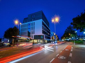 A modern building with a prominent corner entrance and a bicycle lane. - Comfortable Superior Double Stay with Workspace | Pets are Allowed (Stuttgart)