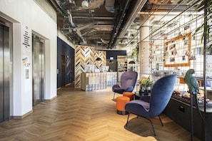 A modern office space with a herringbone-patterned wall, a market area, and a parrot on a stand. - Well-Appointed Superior Twin Room with Workspace (Stuttgart)