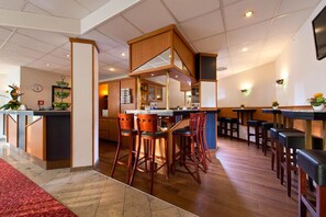 Un restaurant doté d'un bar central, de plusieurs types de sièges, notamment des tabourets hauts et des chaises de bar, et d'un tapis rouge à motifs.
