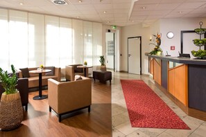 Un hall d’entrée avec des canapés, un comptoir de réception et un tapis rouge.