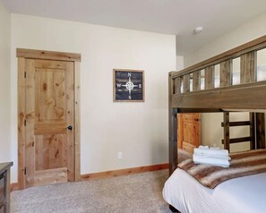 Ein Schlafzimmer mit einem hölzernen Etagenbett, einer Tür und einer Wanddekoration mit Kompass.