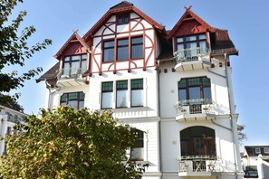 Ein mehrgeschossiges Gebäude mit einem markanten Satteldach und einem Balkon im zweiten Stock.