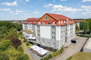 Een hotel met meerdere verdiepingen, een rood dak en een centrale binnenplaats met terras.