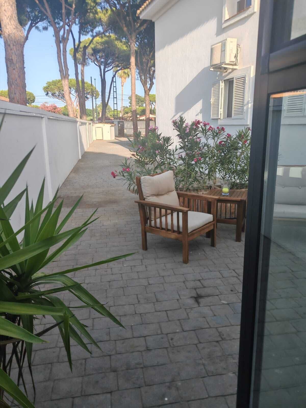 Eine Terrasse mit Holzstuhl und Tisch, einem Topfpflanzen und einem Gebäude mit Fensterläden.