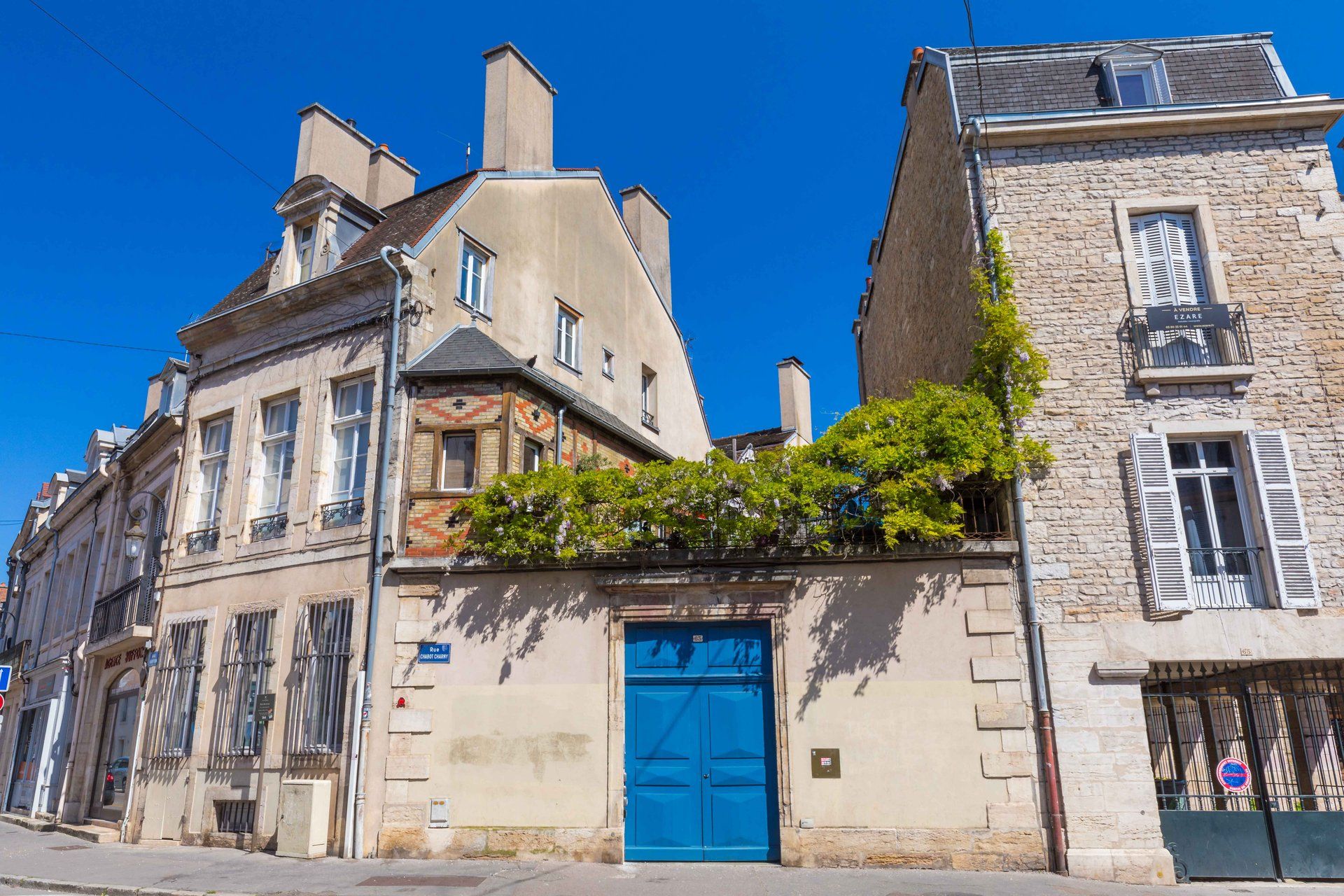 Vista da rua com uma porta azul, um edifício de pedra e uma placa que diz 'Rue de la Clarté'.