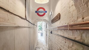 Un passaggio stretto con un cartello circolare che indica la stazione 'Euston', un lampadario e una ringhiera metallica sulla parete destra.