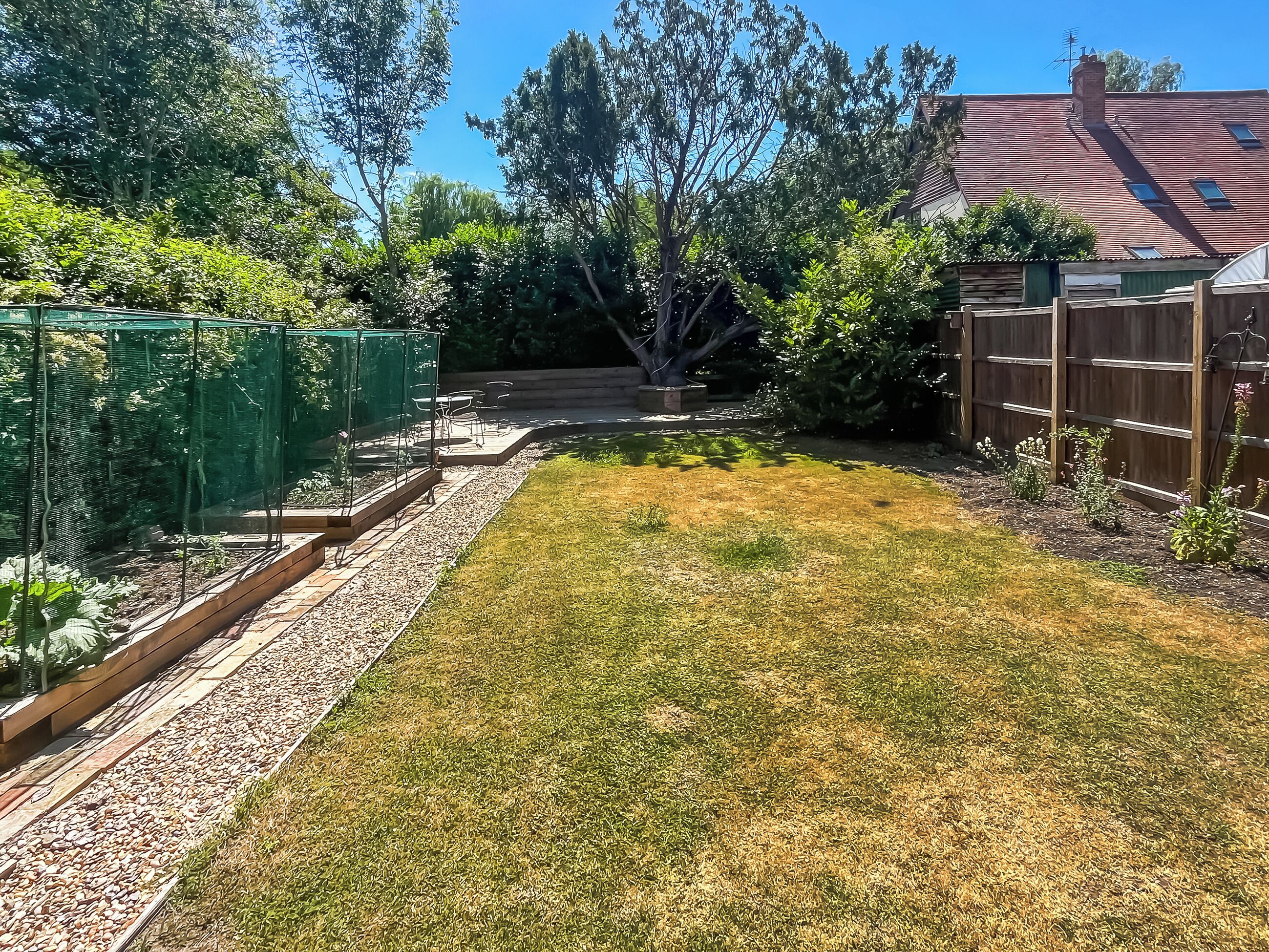 A backyard with a wooden deck, a small garden area, and a fenced section.