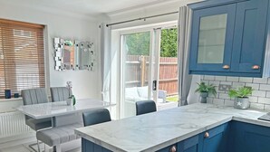 Una cocina moderna con encimera de mármol, armarios azules y un comedor con mesa y sillas.