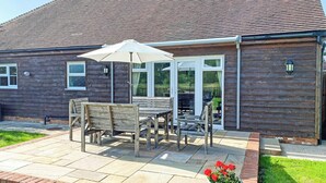 Ein Holzhaus mit einer Terrasse, einem Tisch mit Stühlen und einem Blumentopf.