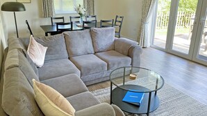 Ein Wohnzimmer mit grauem Sofa, einem Glastisch und einem Essbereich mit Stühlen und Tisch.