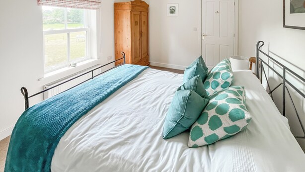 Un dormitorio con cama, ventana, armario y puerta.