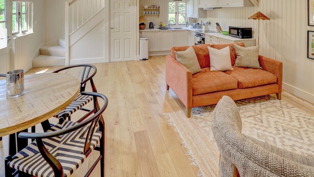 A modern interior with a sofa, dining table, chairs, and a kitchen area.
