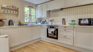 A kitchen with white cabinetry, a built-in oven, and a window with a view of greenery.