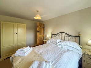 Un dormitorio con cama, armario, mesita de noche y lámpara colgante.