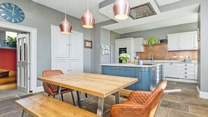 Eine moderne Küche mit Holztisch, Pendelleuchten und einem eingebauten Backofen.