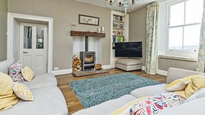 Ein Wohnzimmer mit Kamin, Sofa, Fernseher und Bücherregal.