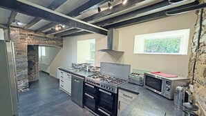 A modern kitchen with a gas stove, oven, and built-in dishwasher. - Hendre Aled Farmhouse (Llanssannan)