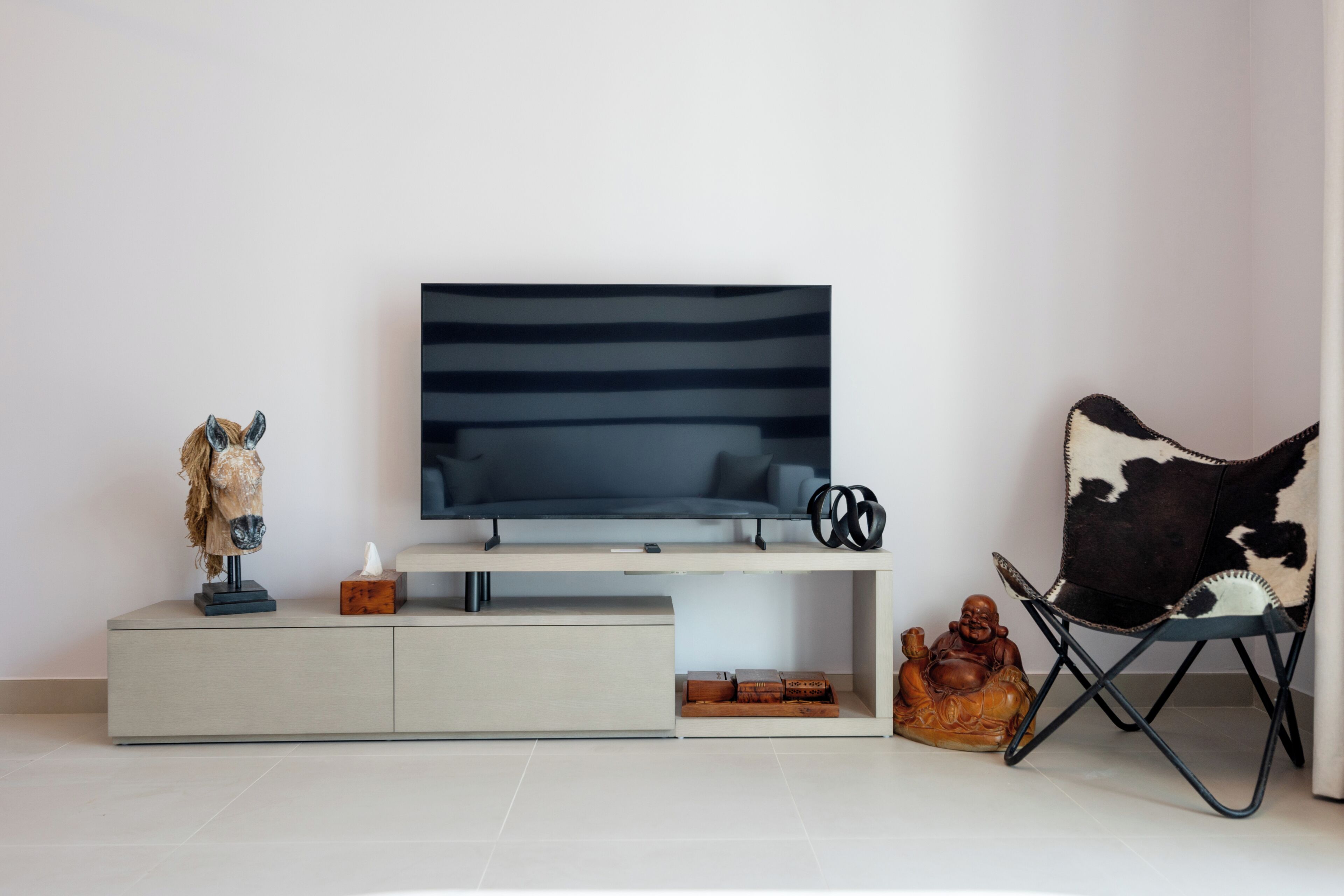 En moderne stue med et fladskærms-tv, et minimalistisk konsolbord og en dekorativ stol.