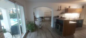 Ein modernes Interieur mit Küche, Essbereich und einer großen Schiebeglasdoor zum Pool.