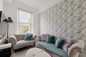 Ein Wohnzimmer mit einer Sofagarnitur, einer Lampe und einer Wand mit Muster.