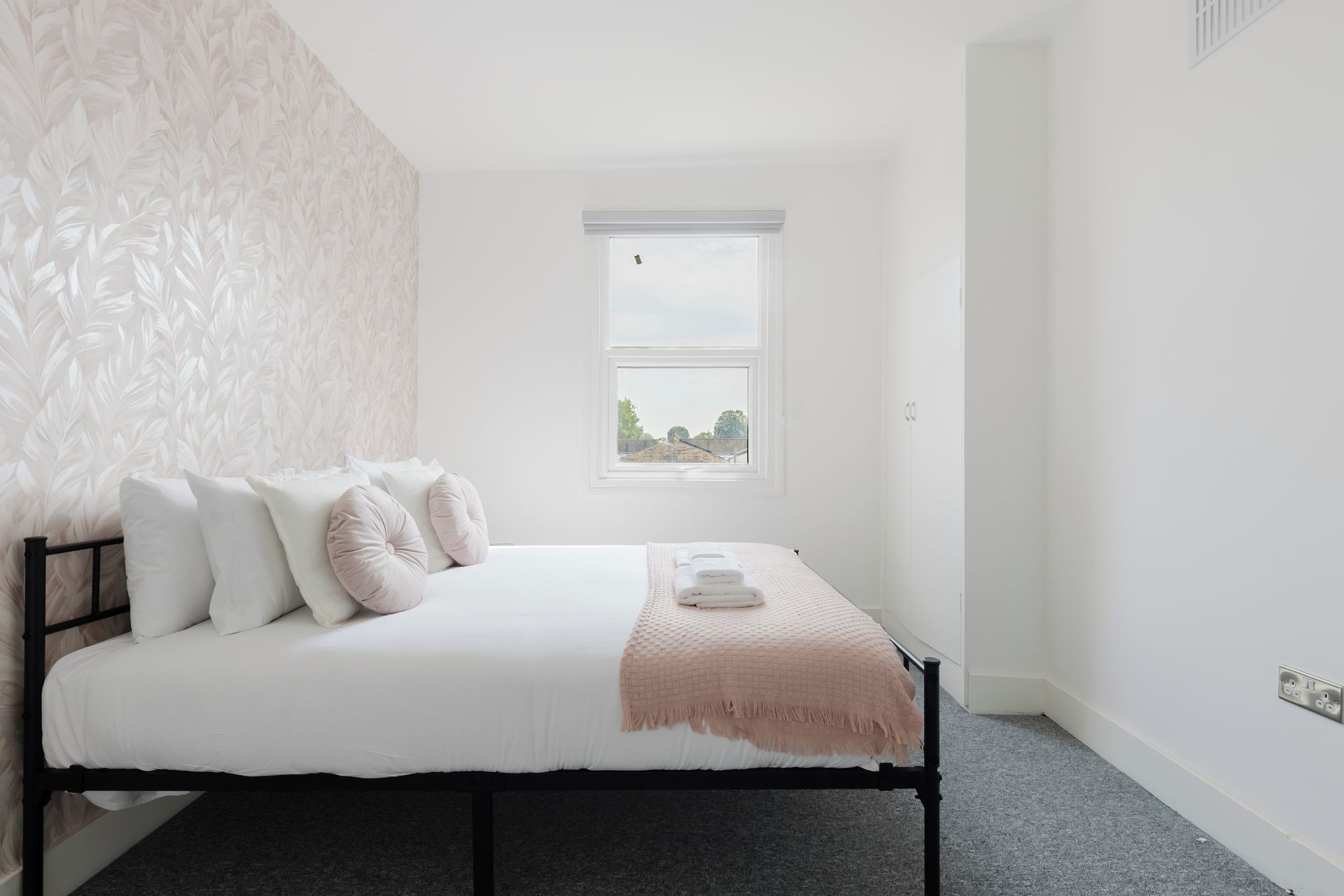 Une chambre à coucher avec un lit, une fenêtre et un mur décoré de motifs.