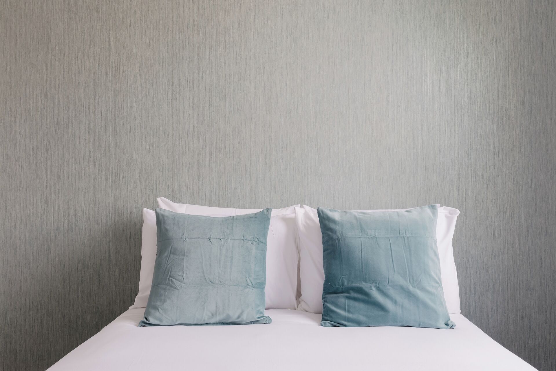 A bed with two pillows against a plain wall.