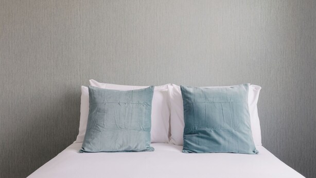 A bed with two pillows against a plain wall. - Newly Renovated 4BDR Home Near Notting Hill (Greater London)