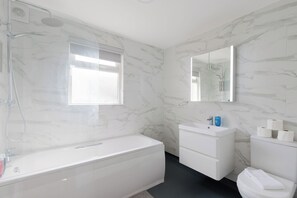 Ein modernes Badezimmer mit Badewanne, Waschbecken, Toilette und Duschbereich.