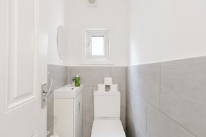 Ein Badezimmer mit Toilette, Waschbecken und einem kleinen Fenster über der Toilette.