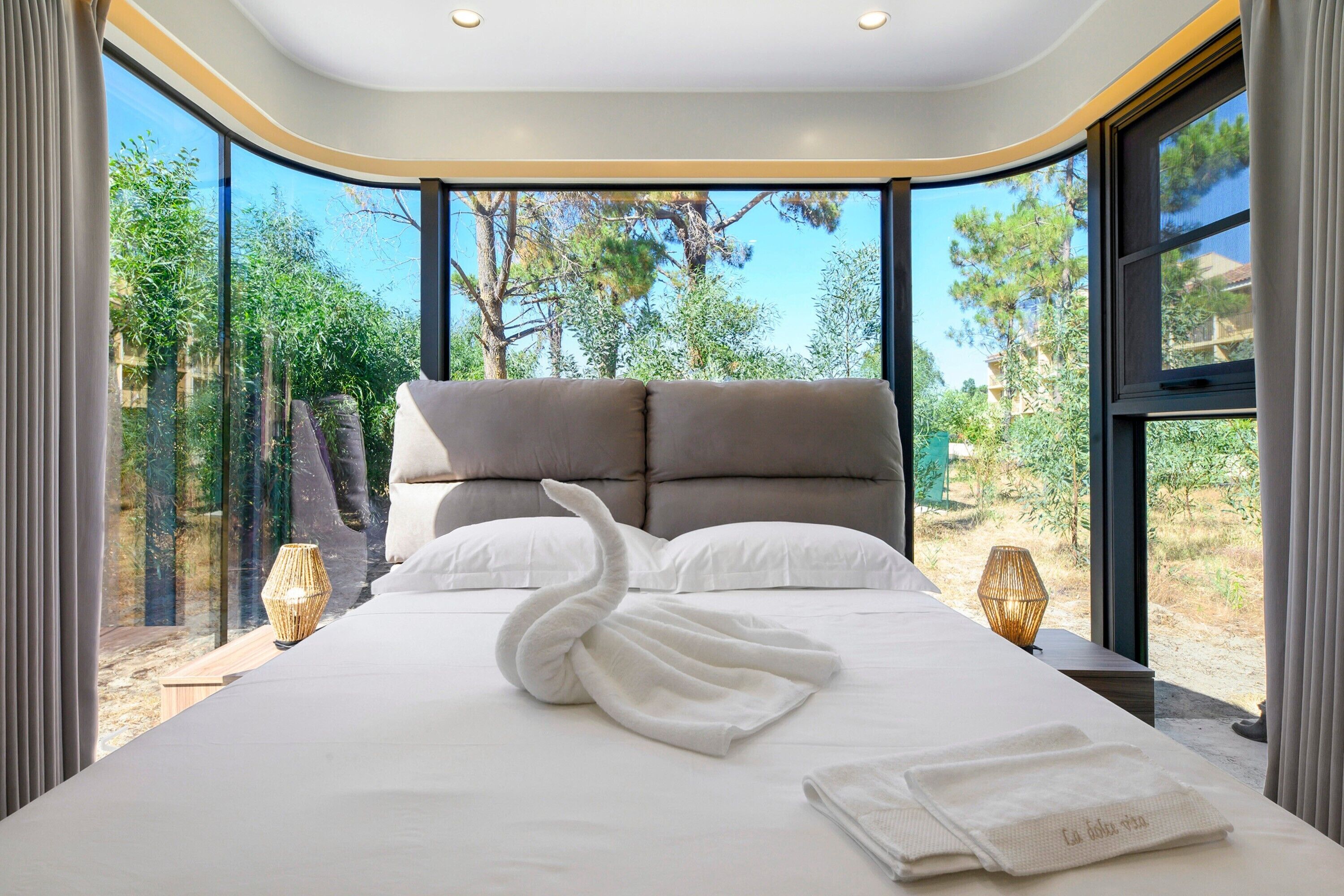 Un dormitorio moderno con una cama grande, dos almohadas y una toalla con forma de cisne.