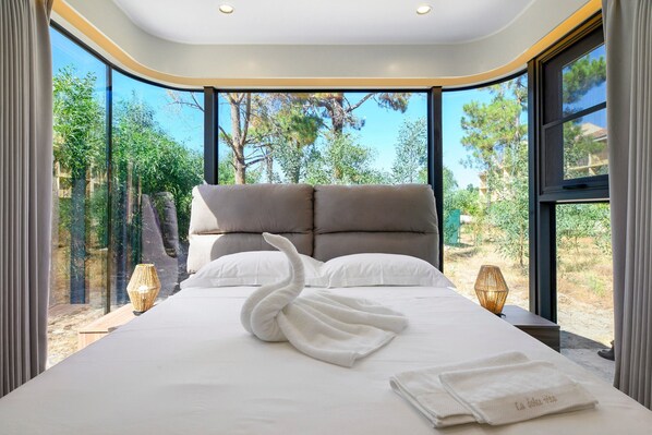 A modern bedroom with a large bed, two pillows, and a swan-shaped towel.