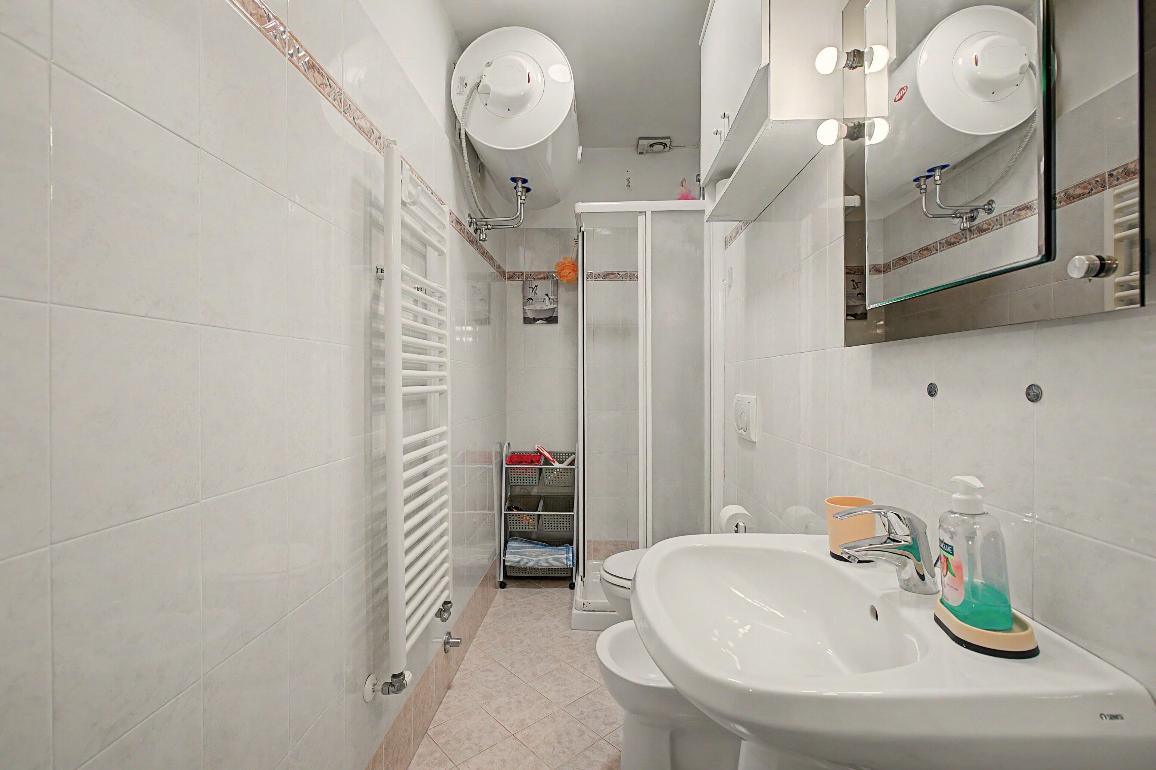Ein Badezimmer mit weißem Waschbecken, Toilette, Dusche und Handtuchhalter.