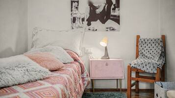 A bedroom with a bed, a chair, a nightstand, and a lamp.