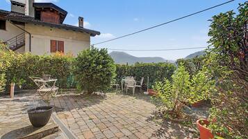 A courtyard with a paved patio, outdoor furniture, potted plants, and a view of mountains.
