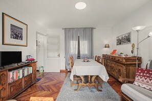 A dining area with a table, chairs, a television, and a bookshelf. - Casa Zio Zeffy Apartment with Mountain View Balcony and Shared Garden (Châtillon)