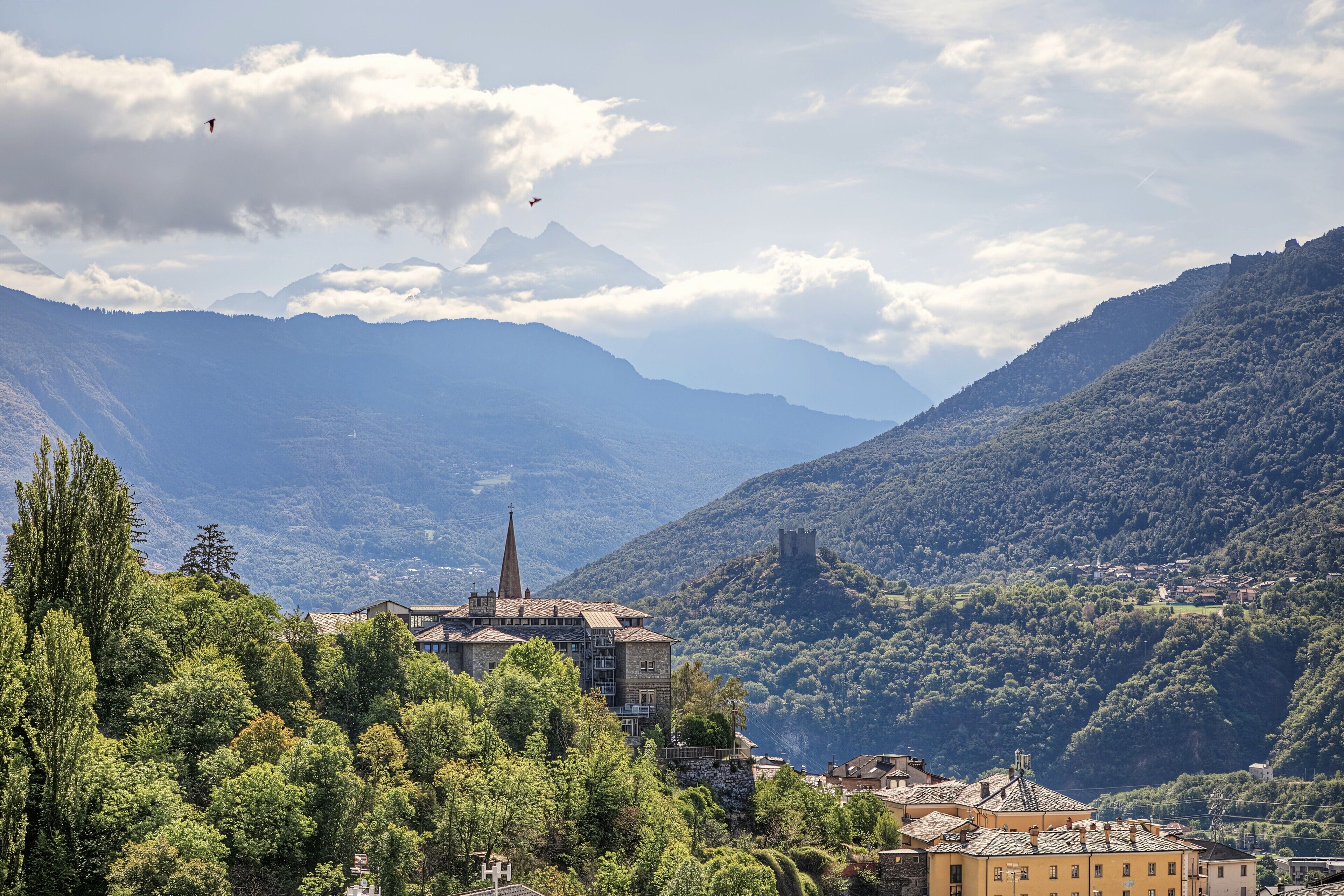 A mountainous landscape with a church, a castle, and a village.