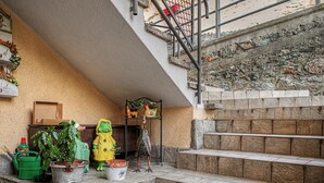 Un escalier avec des marches en pierre menant à un niveau supérieur, une rampe en métal et un mur à la finition texturée.
