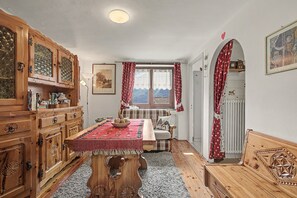 Una habitación tradicional con muebles de madera, una mesa de comedor y una ventana con cortinas.