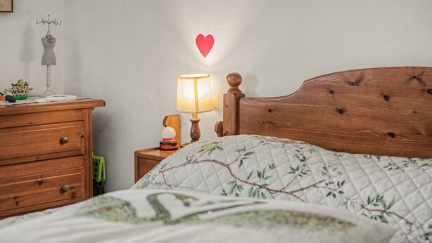 Une chambre à coucher avec une tête de lit en bois, une table de chevet avec une lampe, une commode et un élément décoratif mural.